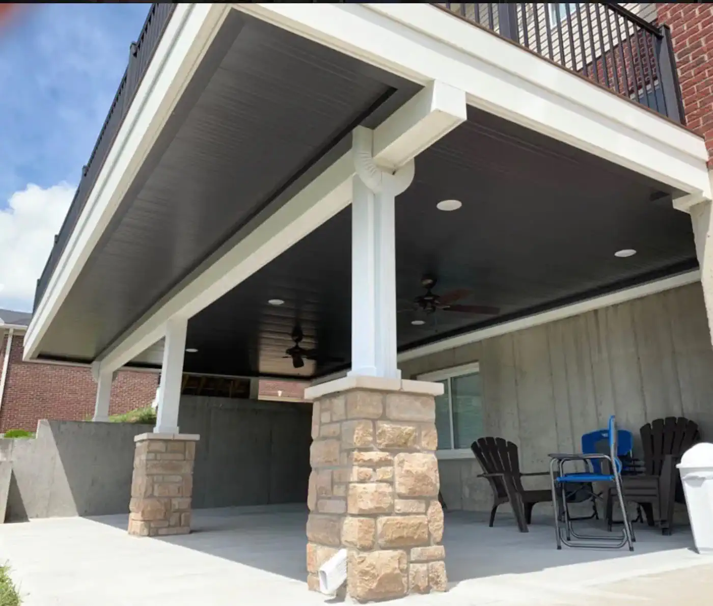 Covered patio with stone pillars, ceiling fans, and outdoor seating