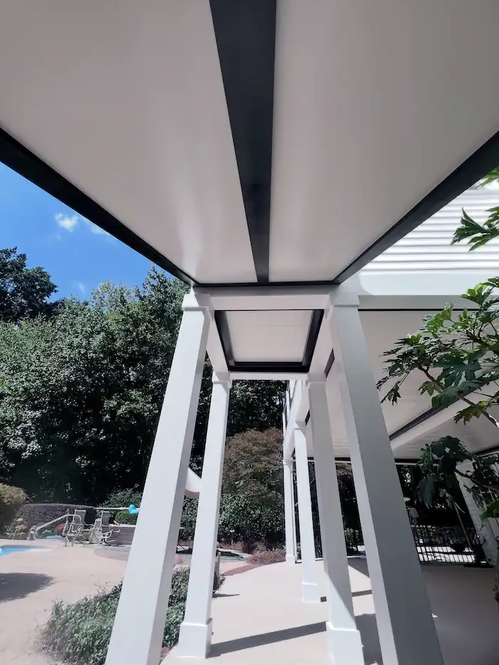 Modern white pergola with black accents overlooking backyard pool