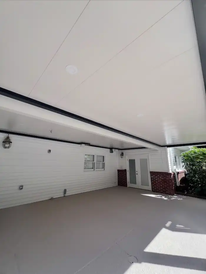Spacious covered carport with white ceiling and brick accents
