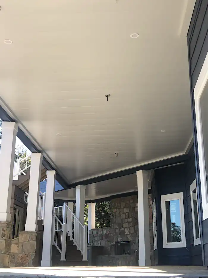 Covered porch with white ceiling, columns, and stone fireplace