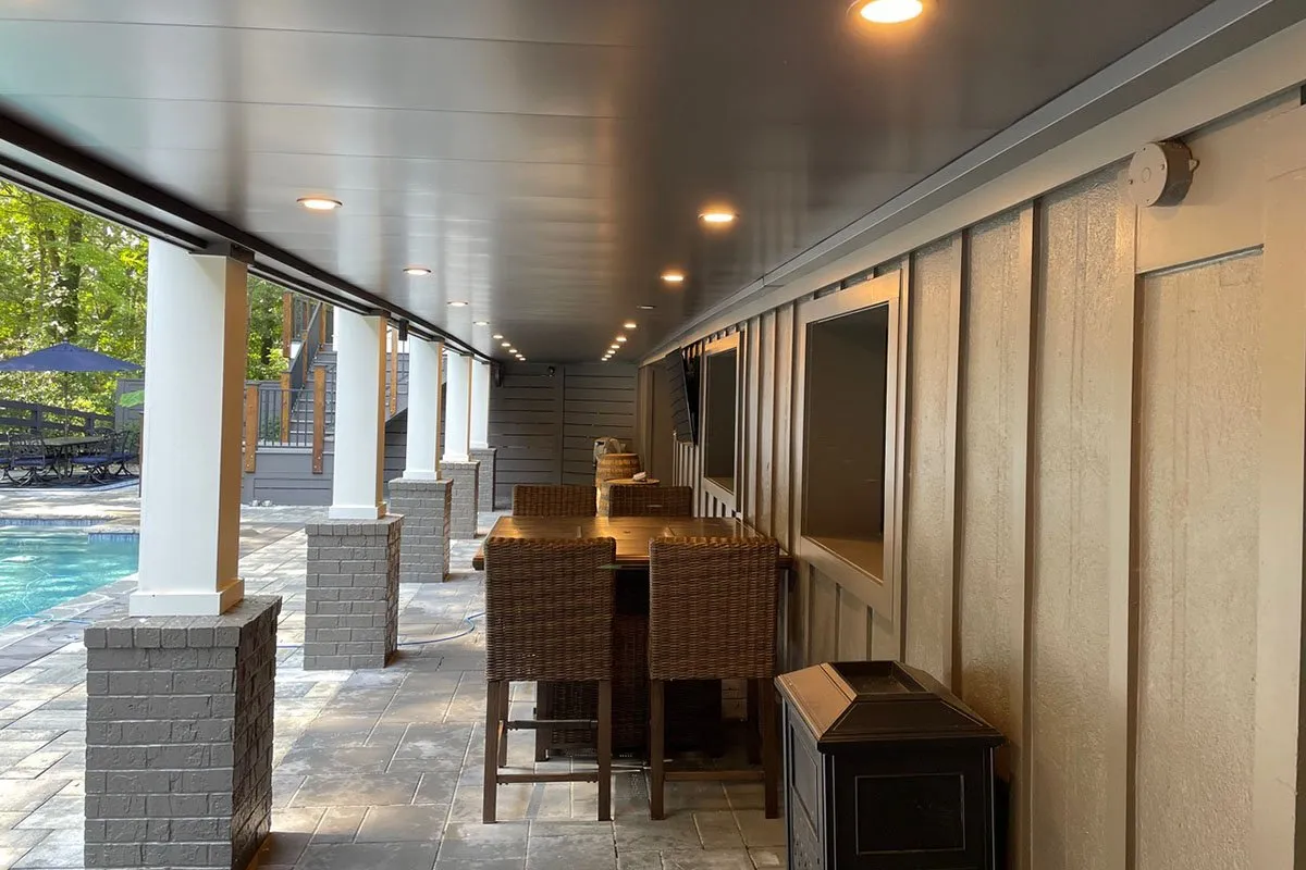 Covered outdoor patio with wicker bar seating beside pool