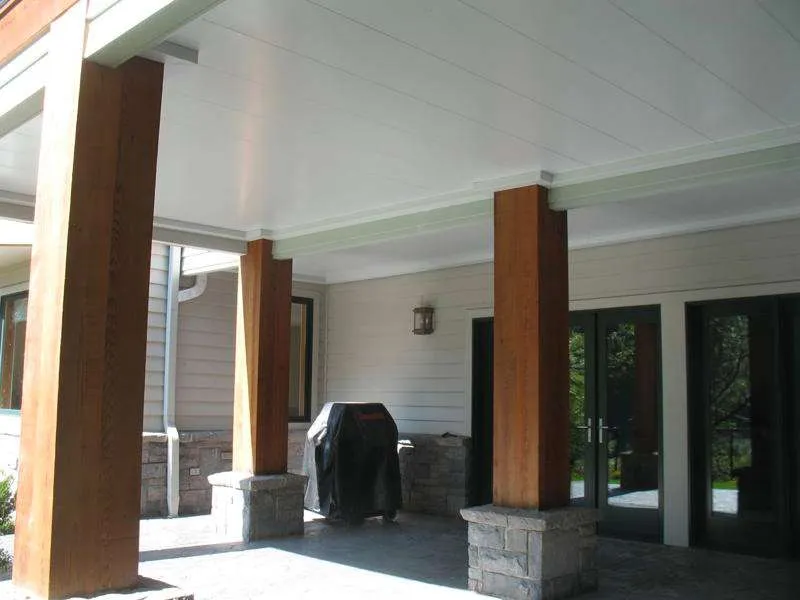 Covered patio with wood columns, stone bases, and grill